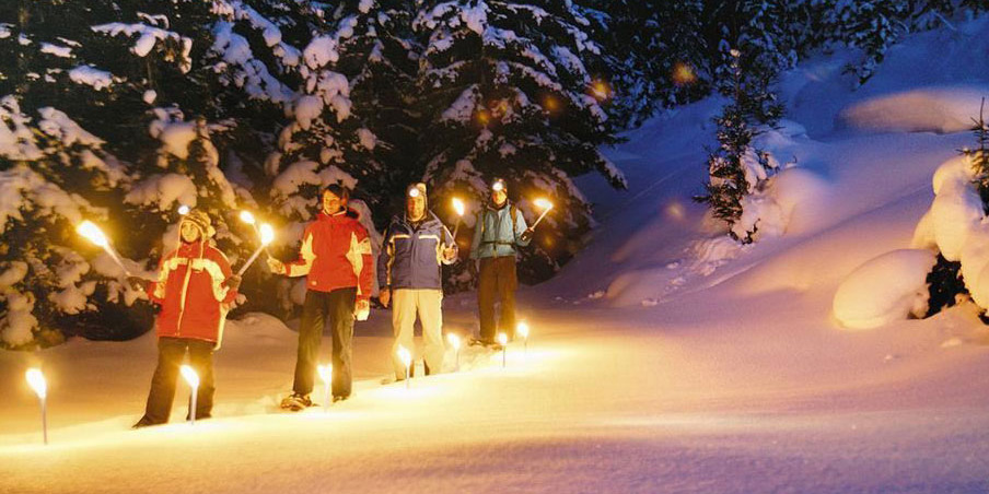 Menschen wandern mit Fackeln im Schnee